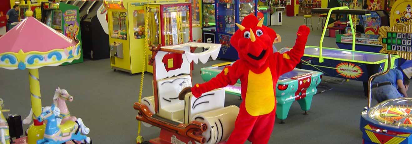 The People's Choice mascot posing in front of arcade games
